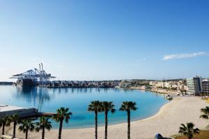 a view of a harbor with palm trees and a beach at Pretty Bay Apartments in Birżebbuġa