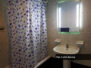 a bathroom with a shower curtain and a sink at SEAFRONT I Pretty Bay Apartments in Birżebbuġa +29 photos