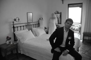 a man in a suit sitting on a bed with a bride at Mando Beachfront in Stafylos