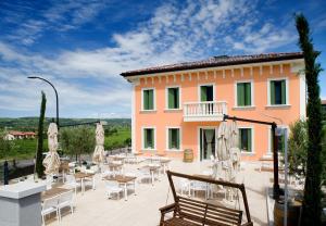 a building with chairs and tables and umbrellas in front of it at Locanda ai Capitelli snc di fiumicetti andrea in Soave