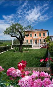 a house with a tree and flowers in the yard at Locanda ai Capitelli in Soave