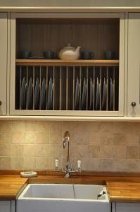 a kitchen with a sink and a shelf with dishes at The Old Coach House, Alltshellach Cottages in North Ballachulish