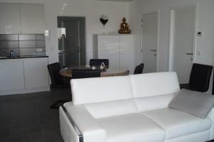 a living room with a white couch and a table at Villa Jalina Sailors Beach in Nieuwpoort
