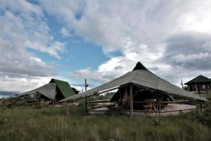 a group of tents in a field with a cloudy sky at CÉU DE AGARTHA Retiros e Vivências in Alto Paraíso de Goiás