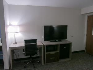 a room with a desk with a television and a chair at Wingate by Wyndham Louisville Airport Expo Center in Louisville