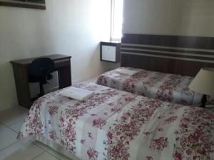 a hotel room with two beds and a desk and a bed at San Marino Hotel in São José dos Campos