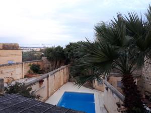 a swimming pool on the roof of a house with palm trees at Gozo Break Farmhouses in Kerċem