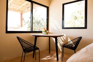 a table and two chairs in a room with two windows at Casa Mono in San Agustinillo