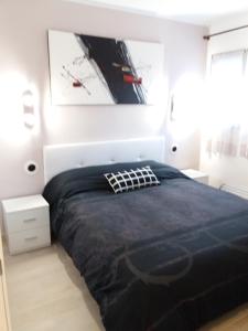 a bedroom with a large bed with a black comforter at Apartamento Torre Sant Salvador in Comarruga