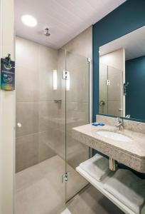 uma casa de banho com um lavatório e uma cabina de duche em vidro. em ibis budget Navegantes Itajai em Itajaí