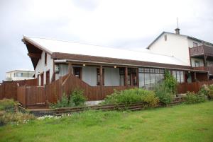 una casa blanca con una valla de madera en un patio en Raven's Bed, en Keflavík