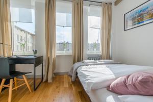 a bedroom with a bed and a desk and windows at Chmielna Warsaw Cental Station P&O Serviced Apartments in Warsaw