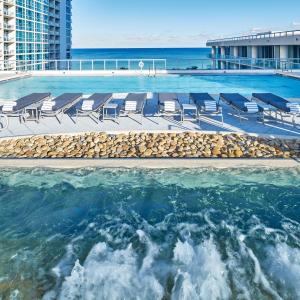 a swimming pool with chairs and the ocean at Carillon Miami Wellness Resort in Miami Beach