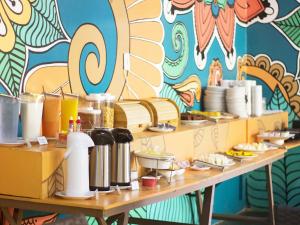 a table with plates of food and a colorful wall at Che Lagarto Hostel Morro De São Paulo in Morro de São Paulo