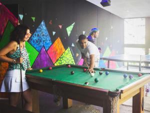 een groep mensen die rond een pooltafel staan bij Che Lagarto Hostel Morro De São Paulo in Morro de São Paulo