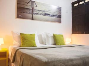um quarto com uma cama com almofadas verdes e brancas em Che Lagarto Hostel Morro De São Paulo em Morro de São Paulo