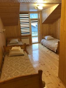 two beds in a room with wooden walls and wood floors at Ресторан-Готель Міжгірʼя in Usteriki