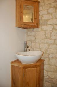 een badkamer met een witte wastafel en een houten kast bij Rataboul in Puylaroque