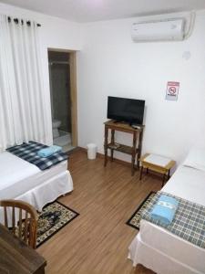 a room with two beds and a flat screen tv at Ipê Rosa Hotel in Bauru