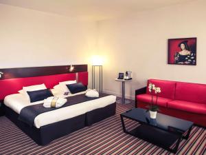 Habitación de hotel con cama y sofá rojo en Mercure Angoulême Hôtel de France, en Angulema