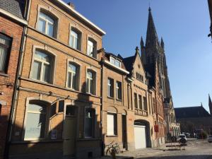 an old brick building with a church in the background at B&B Sabbajon in Ieper