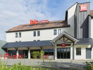 un gran edificio blanco con sillas rojas delante en Ibis Wavre Brussels East, en Wavre