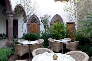 a patio with tables and chairs in a garden at Hotel Casa Blanca 7 in San Miguel de Allende