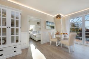 a white room with a dining table and a bedroom at Villa Strandblick 8 in Zingst