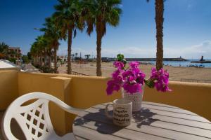 einen Tisch mit einer Vase lila Blumen auf einem Tisch am Strand in der Unterkunft Playa centro in Villajoyosa