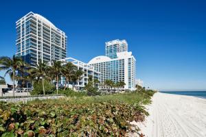 a beach with tall buildings and palm trees and buildings at Carillon Miami Wellness Resort in Miami Beach
