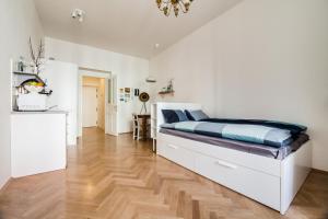 Schlafzimmer mit einem weißen Bett und Holzboden in der Unterkunft Trendy Local Apartment in Prag