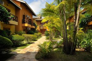 einen Innenhof eines Gebäudes mit Palmen und Büschen in der Unterkunft Ilha Flat Apto 3207 in Ilhabela