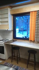 a kitchen with a counter with two stools and a window at Kiiloselän Poropirtti in Kakslauttanen