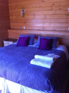 1 cama azul con almohadas moradas y 2 toallas. en B&B de German, en Pucón