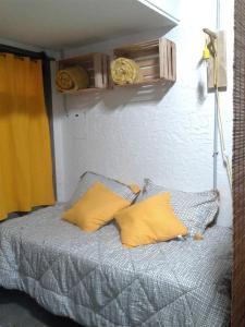 łóżko z 2 żółtymi poduszkami w pokoju w obiekcie 573 APART w mieście Mendoza