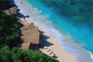an aerial view of a beach with umbrellas and the ocean at The Ungasan Clifftop Resort in Uluwatu