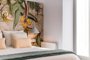 1 dormitorio con 1 cama con una pintura en la pared en FerAla Suites Centro B, en Granada