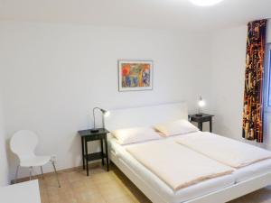 1 Schlafzimmer mit einem weißen Bett, 2 Tischen und einem Stuhl in der Unterkunft Ferienwohnung *Wibkes Hüs* in Wittdün