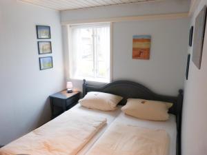 a bedroom with a bed with two pillows and a window at Hüs Sanskiin Ferienwohnung *Brombelbei* in Süddorf
