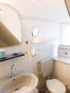 a bathroom with a sink and a toilet and a mirror at Hüs Sanskiin Ferienwohnung *Goodshenk* in Süddorf