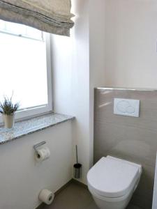 a bathroom with a white toilet and a window at Ferienwohnung *SonnenOase* in Wittdün