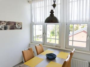 a dining room with a table and chairs and windows at Haus Therese *FeWo 7* in Wittdün