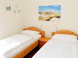 two twin beds in a room with a picture on the wall at Haus Therese *FeWo 3* in Wittdün