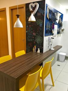 a kitchen with a wooden counter and yellow chairs at Lar Expresso 2222 in Salvador