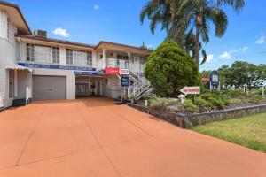 a large white building with a garage and a palm tree at Clifford Park Motor Inn in Toowoomba