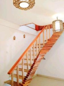 a wooden staircase in a house with a chandelier at Villa Rika in Gili Trawangan