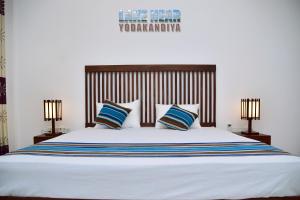 a bedroom with a large white bed with two lamps at Lake Near in Tissamaharama
