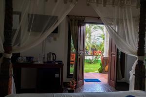 1 dormitorio con 1 cama y puerta a un patio en Lunar Dive Resort en Tulamben