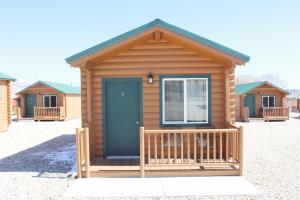 Cabaña de madera con puerta azul y porche en Bryce Valley Lodging en Tropic