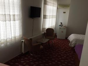 a hotel room with two chairs and a bed and a television at Hotel Birkent in Diyarbakır